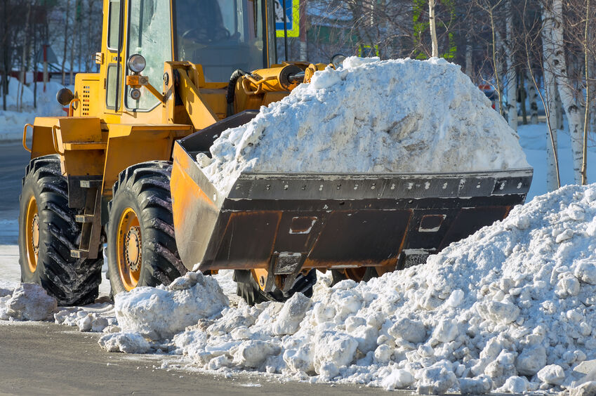 The bulldozer cleans from the road old snow